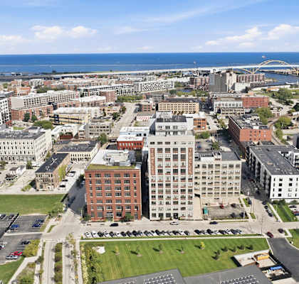 A cityscape with buildings and a parking lot in the foreground.