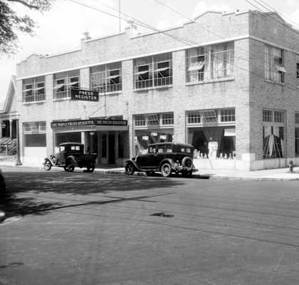 an old photo of a building with cars parked outside of it