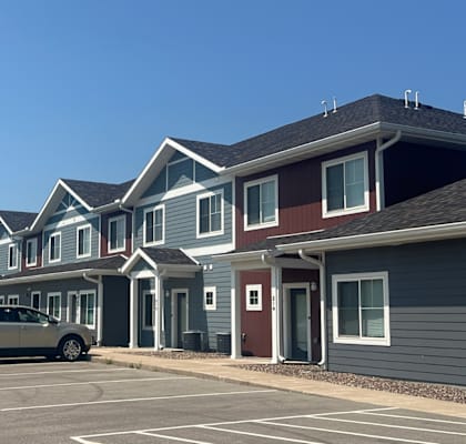 A row of houses with cars parked in front.