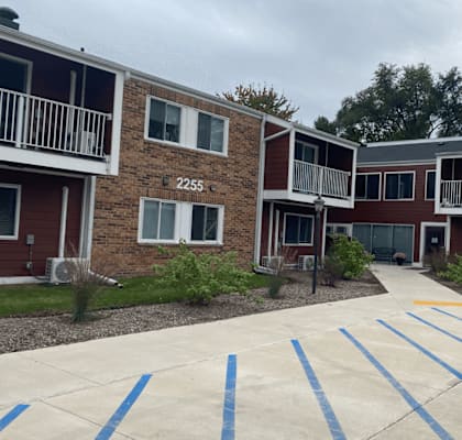 A parking lot in front of apartment buildings with blue stripes on the pavement.