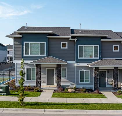 Gray community home with landscaped entryway and front door.