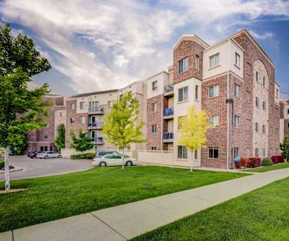 The exterior of Bridges Apartment Homes, with a brick apartment building with green grass and a sidewalk. 