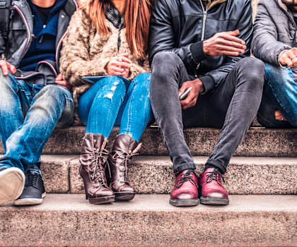 A group of people sitting on steps wearing various types of footwear.
