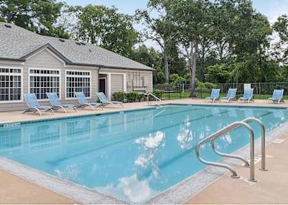 a swimming pool with chairs and a building in the background
