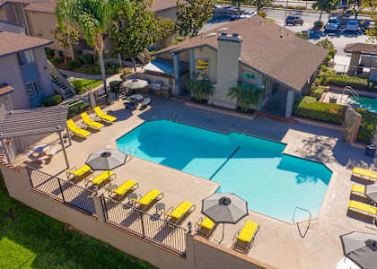 an aerial view of a swimming pool and patio with yellow chairs and umbrellas