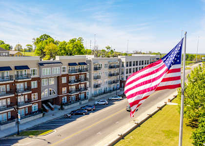 A large American flag flies in front of a row of apartment buildings at The Heights Apartments, Alabama