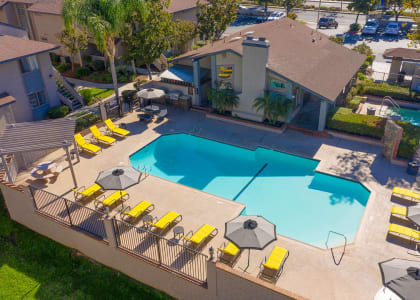 an aerial view of a swimming pool and patio with yellow chairs and umbrellas