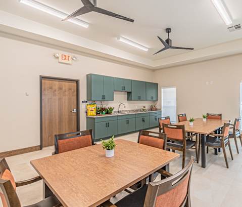 a dining area with tables and chairs and a kitchen with green cabinets