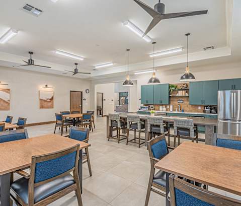 a large dining room with tables and chairs and a kitchen