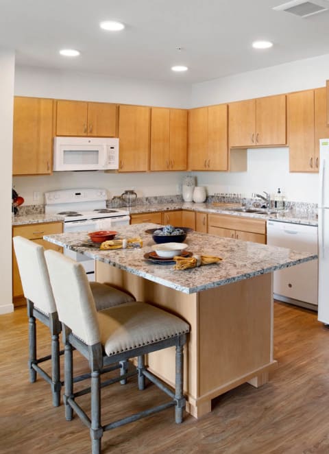 a kitchen with wooden cabinets and a marble counter top at The Legends of Blaine 55+, Minnesota, 55449