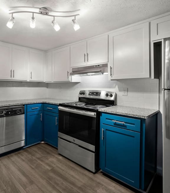 A kitchen with blue cabinets and stainless steel appliances at Pines at Lawrenceville Apartments in Decatur, Georgia