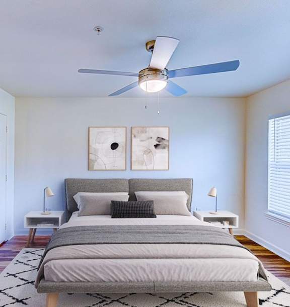 A living room with a white couch, a guitar, and a large window.