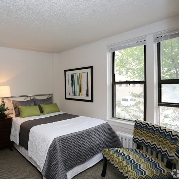 A bedroom with a bed, nightstand, and window.