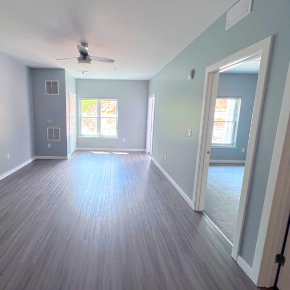A room with a ceiling fan and wooden flooring.