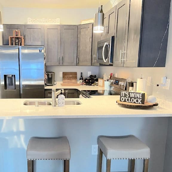 A kitchen with a white countertop and bar stools.