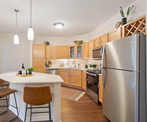 a kitchen and dining area with stainless steel appliances and wooden cabinets at The Bluffs at Nine Mile Creek, Minnesota