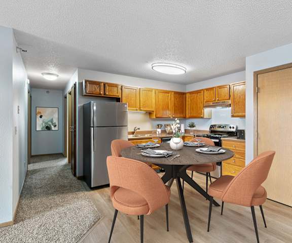 a dining room with a table and chairs and a kitchen with a refrigerator
