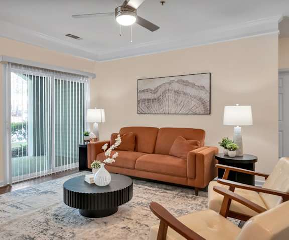 A living room with a brown couch, a coffee table, and a ceiling fan.