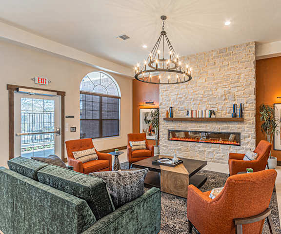 a living room with chairs and a fireplace and a chandelier