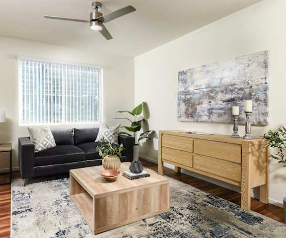 A living room with a black couch, a wooden coffee table, and a painting on the wall.