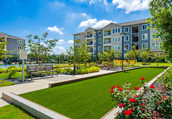 A sunny day at a residential complex with a well-maintained garden and apartment buildings.