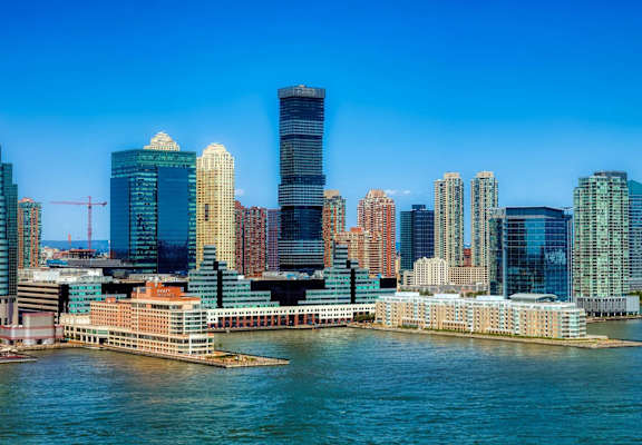 A city skyline with tall buildings and a body of water in the foreground.