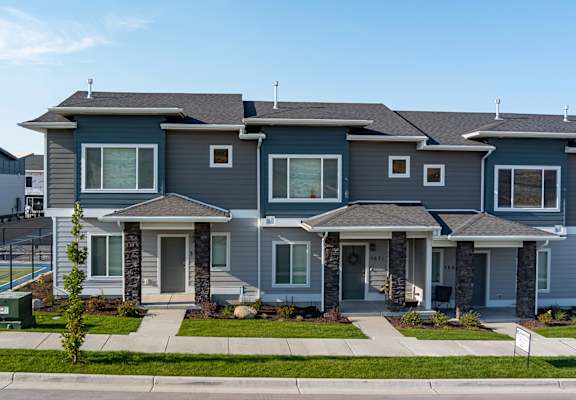 Gray community home with landscaped entryway and front door.