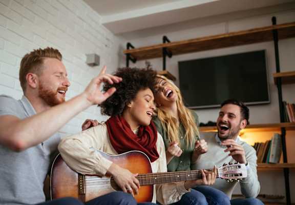 group of friends in living room playing guitar and singing at TOWNSHIP Apartments, CANBY, OR 97013