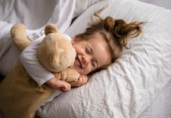 little girl snuggling a teddy bear in bed at TOWNSHIP Apartments, Oregon 97013
