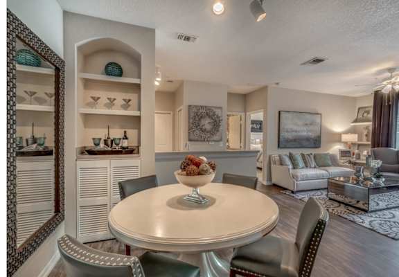 View of furnished model from entry looking into dining room with built-in shelving and living room.