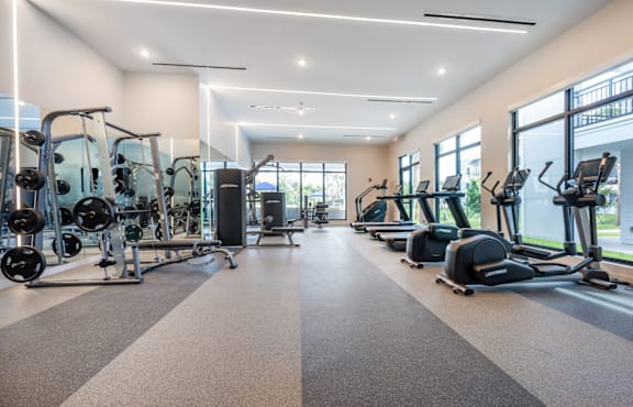A spacious gym with a variety of equipment including treadmills, elliptical machines, and weight machines.