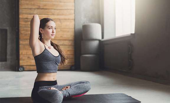 a woman sitting on a yoga mat in a yoga studio