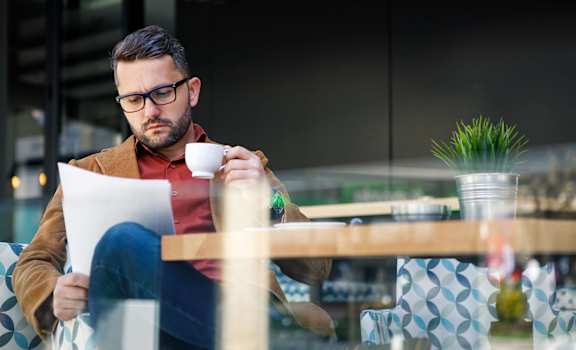 Man drinks coffee while reading at Haven at Uptown