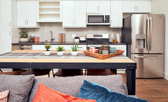 A modern kitchen with a dining table and a couch with pillows. at Main+Nine, Riverside, 92501
