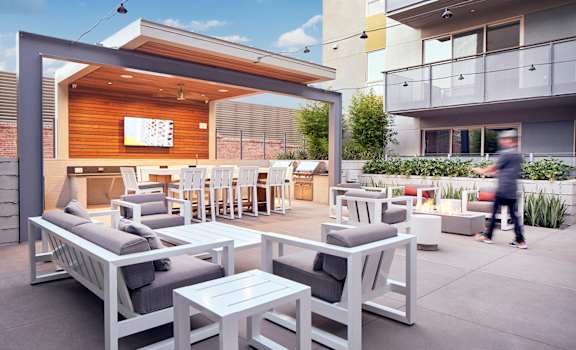 A patio with white furniture and a person walking. at Main+Nine, California, 92501