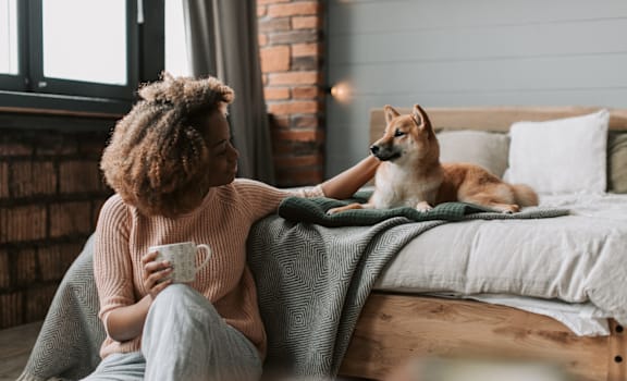 a woman sitting on a bed with her dog