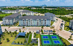 A large building with a tennis court in front of it.