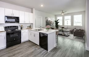 A modern kitchen with black appliances and white cabinets.