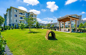 A large grassy area in front of apartment buildings with a wooden pavilion.