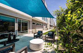 A patio with a blue awning and furniture.
