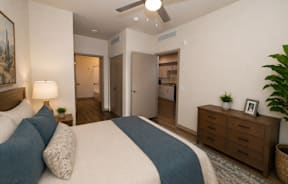 A bedroom with a bed, nightstand, and a painting on the wall.