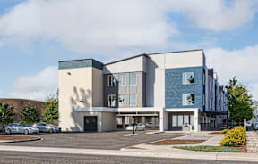A modern building with a parking lot in front.