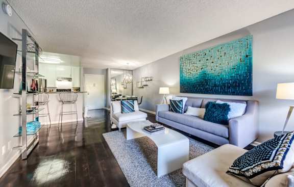 A living room with a white couch and a blue abstract painting on the wall.