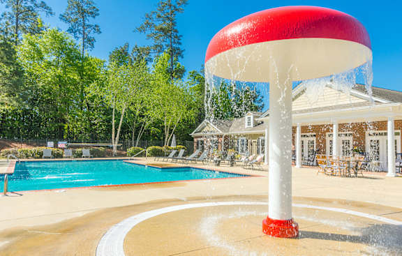 a water fountain with water spraying out of it near a pool