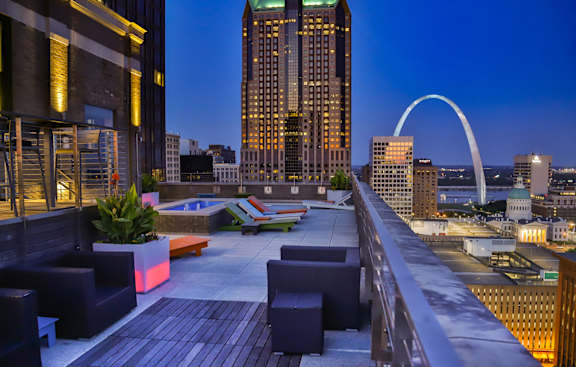 A rooftop patio with a view of the city skyline and a large arch at Arcade Apartments, St Louis, MO, 63101