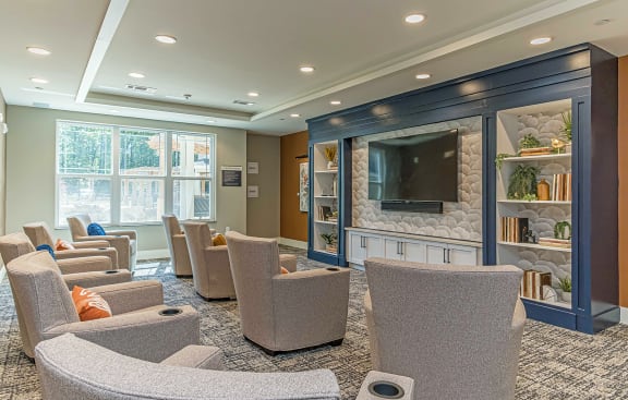 a room with chairs and a television in front of a wall of windows