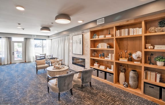 a living room with chairs and a table and a fireplace at Heritage at Church Ranch 55+ Apartments, Westminster , 80021
