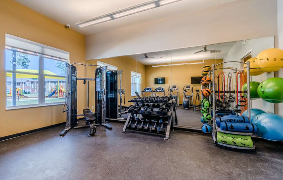 a gym with weights and cardio equipment and a window at Lakecrest Village, Houston Texas