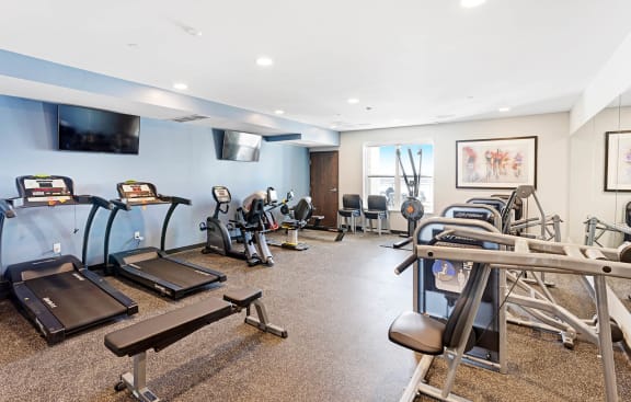 a gym with various exercise equipment and a television at The Legends of Blaine 55+, Blaine Minnesota