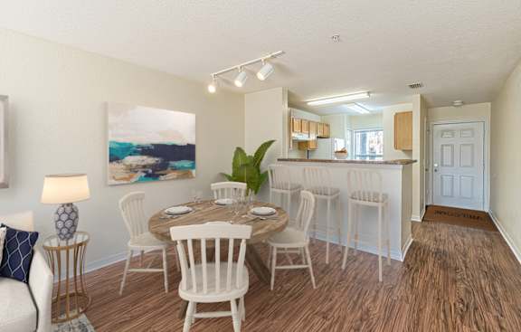 a dining area with a table and chairs and a kitchen in the background